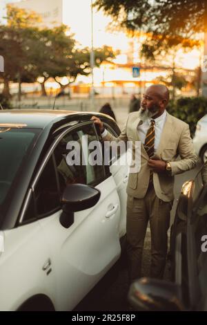 Lissabon; Vertikalaufnahme eines stilvollen schwarzen Mannes mit weißhaarigem Bart, cremefarbenem Anzug, weißem Hemd und gelb-brauner gestreifter Krawatte, Öffnung Stockfoto