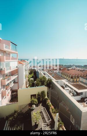 Lissabon; vertikal; Weitwinkel; Blick von einem Apartment mit lachsfarbener Fassade auf die Stadt, der den Tejo und die Nachbildung des Goldenen Stockfoto