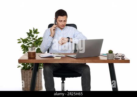 Geschäftsmann, der mit einem Notebook arbeitet und telefoniert Stockfoto