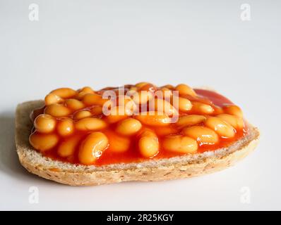 Gebackene Bohnen auf einer Scheibe Toast auf weißem Hintergrund Stockfoto