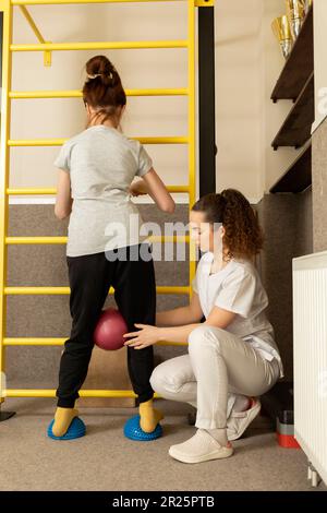 Behindertes Mädchen Im Teenageralter Mit Arzt Macht Körperliche Übungen Im Rehabilitationsraum. Kind Mit Besonderen Bedürfnissen. Rehabilitation. Zerebralparese. Motor Stockfoto