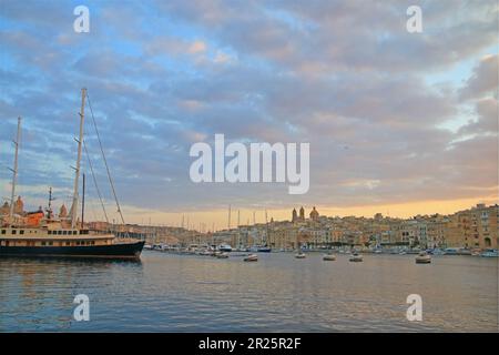 Das Foto wurde in Birgu auf der Insel Malta aufgenommen. Das Bild zeigt eine ruhige Landschaft des Hafens in den Strahlen der untergehenden Sonne, wit Stockfoto