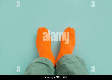 Die Füße eines Mannes in orangefarbenen Socken und Jeans. Im Hintergrund eines Minuteman. Draufsicht. Stockfoto