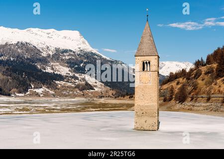 Berühmter Glockenturm aus dem 14. Jahrhundert im gefrorenen Reschensee, dem Reschen-See und dem alten untergetauchten Dorf Graun im Vinschgau-Tal, Südtirol, Italien. Stockfoto