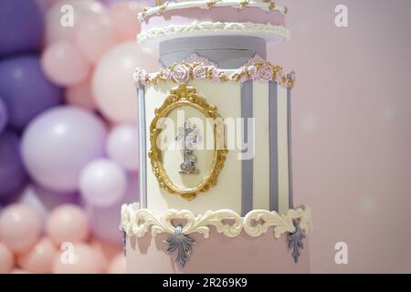 Kind 1. Geburtstag Prinzessinenkuchen, rosa und lila Kuchen zum ersten Geburtstag Nahaufnahme und isoliert auf pinkfarbenem Hintergrund mit Ballons. Stockfoto