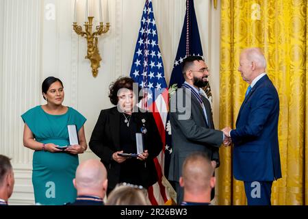 Washington, Vereinigte Staaten Von Amerika. 17. Mai 2023. Washington, Vereinigte Staaten von Amerika. 17. Mai 2023. US-Präsident Joe Biden, richtig, gratuliert New York City Police Detective Sumit Sulan, Center, mit der Public Safety Officer Medaille of Valor während einer Zeremonie im East Room des Weißen Hauses, 17. Mai 2023 in Washington, DC Gabina Mora, 2. links, Mutter des gefallenen Detective Wilbert Mora von der New York City Polizei, und Dominique Rivera, links, Ehefrau des gefallenen New York City Detective Jason Rivera nahm Medaillen in ihrem Namen an. Kredit: Adam Schultz/White House Photo/Alamy Live News Stockfoto