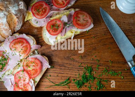 Sandwich, Häppchen mit Schnittlauch auf einem hölzernen Schneidebrett, zerstoßenes Sandwich, morgendliches Frühstück. Stockfoto