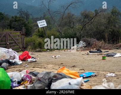 Fliege, die Müll auf dem Land in der Nähe des Verbotsschilds auf Spanisch - Chile kippt Stockfoto