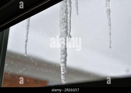 Eiszapfen hängen vor dem Fenster. Stockfoto
