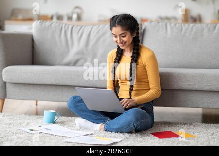 Glückliche Freiberuflerin Aus Indien, Die Zu Hause Mit Laptops Und Papern Arbeitet Stockfoto