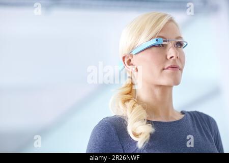 Zukunftstechnik jetzt. Eine junge Frau, die in einem Büro steht und eine intelligente Brille trägt. Stockfoto