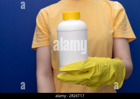 Frau In Gelben Handschuhen Hält Weiße Flasche Mit Rohrreiniger Granulat. Beseitigung Von Verstopfungen Im Spülbecken, Dusche Mit Spezialchemikalien. Verstopfung Reinigen Stockfoto