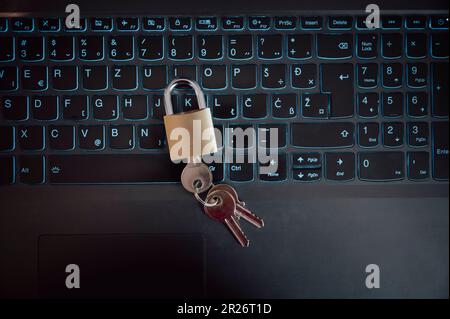 Ansicht von oben: Goldenes Vorhängeschloss mit Schlüsseln auf der Tastatur des Laptops. Konzeptionelles Bild von Cybersicherheit und Firewall. Stockfoto