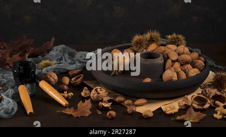 Im Herbst trockene Früchte auf dem Tisch mit einem Nusskrackwerkzeug und einer schwarzen Keramikplatte. Stockfoto