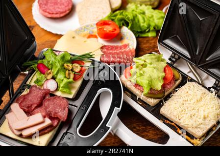 Verschiedene Sandwiches in einem Sandwichautomaten auf Holzhintergrund mit verschiedenen Zutaten. Platz für Text. Stockfoto