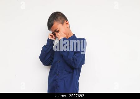 Trauriger Junge, der ein blaues Hemd trägt, isoliert auf weißem Hintergrund Stockfoto