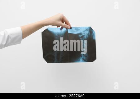 Arzt untersucht Hals-MRT-Bild auf hellgrauem Hintergrund, Nahaufnahme Stockfoto