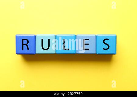 Wortregeln aus Holzwürfeln mit Buchstaben auf gelbem Hintergrund Stockfoto
