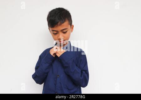 Trauriger Junge, der ein blaues Hemd trägt, isoliert auf weißem Hintergrund Stockfoto