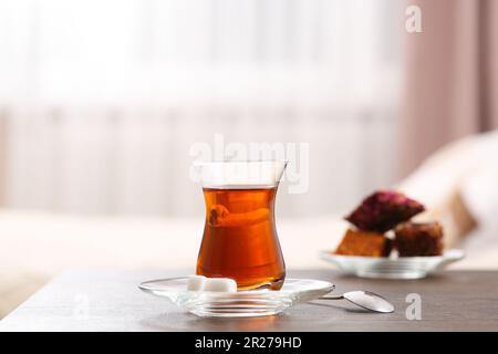 Glas mit traditionellem türkischem Tee und Plätzchen auf dem Tisch im Innenbereich Stockfoto