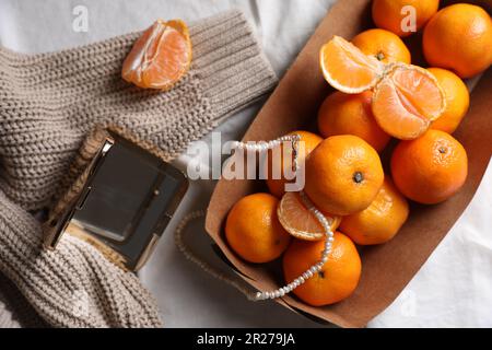 Pappschachtel mit frischen, reifen Tangerinen und Dekor auf weißem Stoff, flach liegend Stockfoto