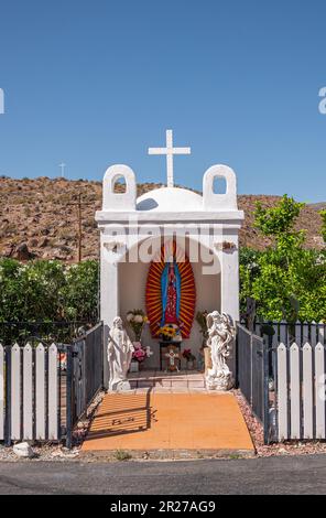 Borrego Springs, CA, USA - 24. April 2023: Statue der Jungfrau Maria von Guadalupe in weißer Nische außerhalb der Kirche Saint Richards Flowers, Cross, Angel Stockfoto