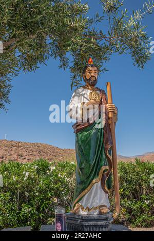 Borrego Springs, CA, USA - 24. April 2023: St. Jude Thaddeus farbenfrohe Statue in der St. Richards Kirche vor blauem Himmel, umgeben von grünem Laub. S Stockfoto