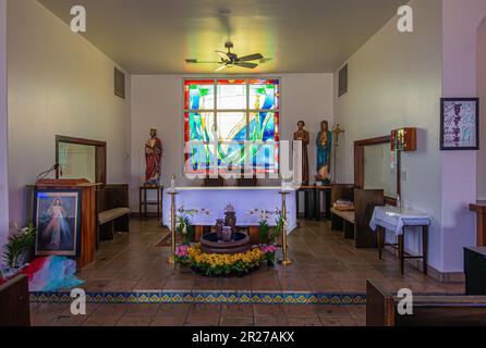 Borrego Springs, CA, USA - 24. April 2023: In der katholischen Kirche Saint Richards. Chancel-Bereich mit weißem Altar, Statuen, Kreuzen, Blumen und Stockfoto