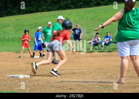 Junge Mädchen laufen während eines Softballspiels auf die Heimplatte zu Stockfoto