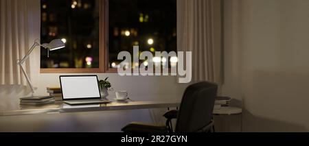 Moderner, minimaler Arbeitsplatz in Ihrem Zuhause bei Nacht mit Laptop-Computer-Modell mit leerem Bildschirm, Tischleuchte und Zubehör auf einem Tisch vor dem Fenster bei Nacht Stockfoto