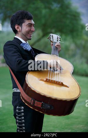 Lächelnder Mariachi-Musiker, der in Tucson, Arizona, eine guitarrón spielt. Schließen. Stockfoto