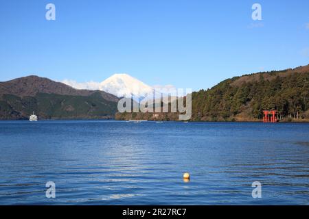 Der Schneebedeckte Mt. Fuji, Ausflugsboote und die Tore zum Hakone-Schrein spiegeln sich im Ashi-See wider Stockfoto