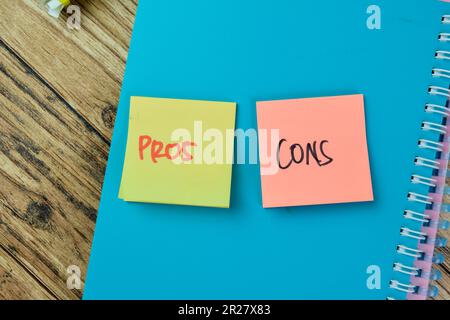 Das Konzept der vor- und Nachteile schreibt auf Haftnotizen, die auf einem Holztisch isoliert sind. Stockfoto