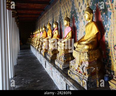 Buddha-Statuen in den Hallen rund um die Ordnungshalle in Wat Arun ( Tempel der Morgenröte ) in Bangkok, Thailand. Stockfoto