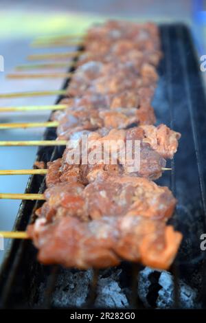 Gegrillte Schweinespieße, die auf Holzkohle kochen. Bangkok, Thailand. Stockfoto