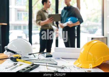 Ingenieurteams, die zusammenarbeiten und Arbeiterhelme auf der Baustelle in einer modernen Stadt halten.Asiatisches Industrieteam Stockfoto