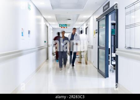 Verschwommene Bewegung von verschiedenen Ärzten und medizinischem Personal im belebten Krankenhausflur, Kopierraum Stockfoto