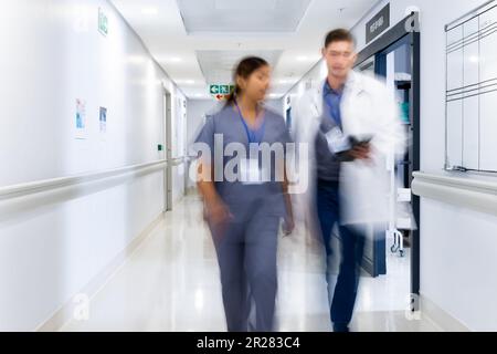 Verschwommene Bewegung von verschiedenen Ärzten und medizinischem Personal im belebten Krankenhausflur, Kopierraum Stockfoto