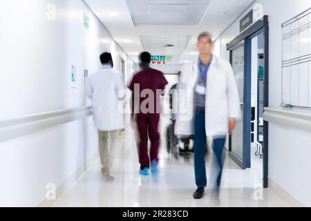 Verschwommene Bewegung verschiedener Ärzte und medizinischem Personal im belebten Krankenhausgang Stockfoto