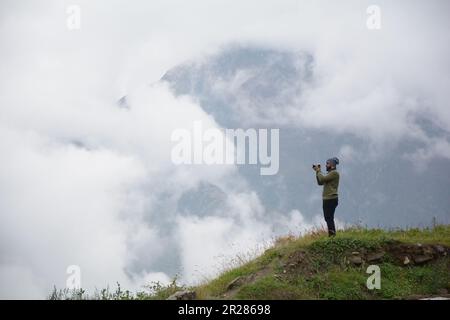 Auf der Suche nach der perfekten Aufnahme: Ein Fotograf nimmt die atemberaubende Aussicht von einem Berg auf. Stockfoto