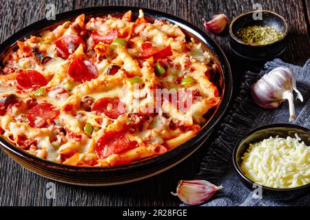 Pizzakasserolle mit zarter Penne Pasta, gebräuntem Rindfleisch, Peperoni, Oliven, Paprika, Und Käse in Marinara-Sauce in Gericht Stockfoto