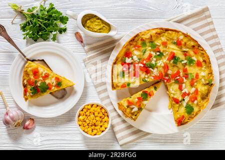 Vegetarisches Green Chile Enchilada – Auflauf aus Maistortillas mit gekühlten Bohnen, Mais, Sauce und Käse, garniert mit Pico de gallo, flach liegend Stockfoto