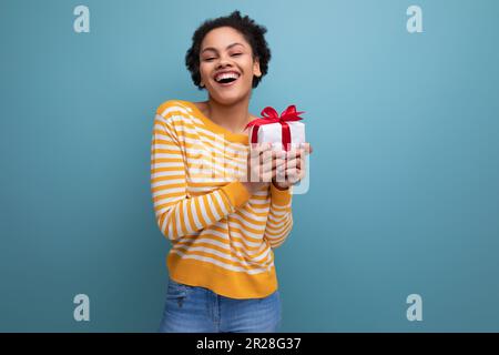 Fröhliche afro brunette 20s lateinische junge Frau mit Geschenk Stockfoto