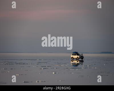 Aufregendes 4x4-Abenteuer über den atemberaubenden Salar de Uyuni bei Sonnenuntergang. Genießen Sie die Schönheit der riesigen Salzebenen in der einzigartigen bolivianischen Landschaft. Stockfoto