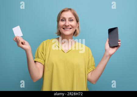 Eine blonde, reife Frau kauft online mit ihrer Geldkarte Stockfoto