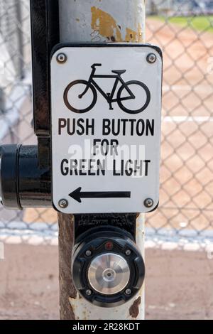 Fahrradtaster für grünes Lichtzeichen an der rostigen Stange. Stockfoto