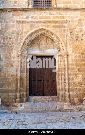 Die alte Holztür in der kunstvoll verzierten Steinmauer der Kirche Stockfoto