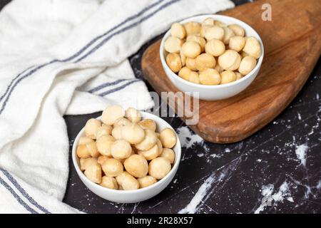 Macadamianüsse. Geschälte Macadamianüsse in einer Keramikschüssel. Superfood. Vegetarisches Speisenkonzept. Gesunde Snacks Stockfoto