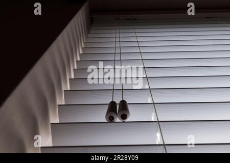 Nahaufnahme der venezianischen Jalousie und Kabel auf der Innenseite des Hausfensters Stockfoto