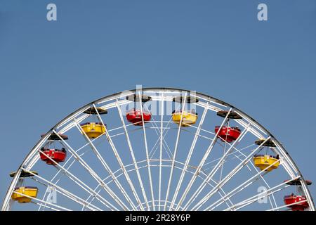 Ein Blick auf die obere Hälfte eines Riesenrads mit bunten Hütten an einem sonnigen Tag Stockfoto